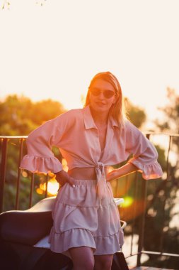 Gün batımında güzel bir kadın denize bakan bir terasta duruyor. Yüksek kalite fotoğraf