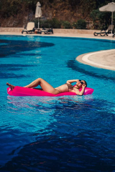 Havuzdaki Pembe Şişme Yatakta Mayo Giymiş Seksi Bir Kadın Yatıyor — Stok fotoğraf