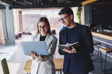Beautiful european business woman and business man looking at the screen of a laptop computer and talking to a businessman in the office.