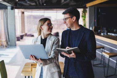 Beautiful european business woman and business man looking at the screen of a laptop computer and talking to a businessman in the office.