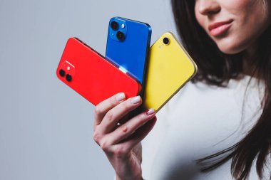 New bright phones in the hands of a woman. Hands of a woman holding several smartphones.