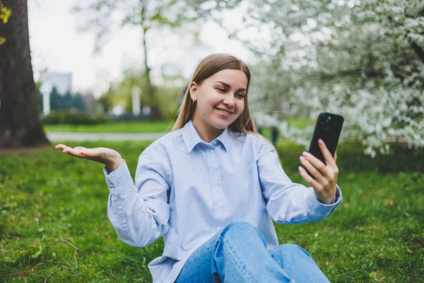 Şehir caddesinde akıllı telefon kullanarak yürüyen mutlu bir kadın. Güneş gözlüklü iş kadını dışarıda, ağacın altında cep telefonu kullanıyor. Kız mesaj yazıyor, sohbet ediyor, web sayfası kayıyor. Kameraya bakın.