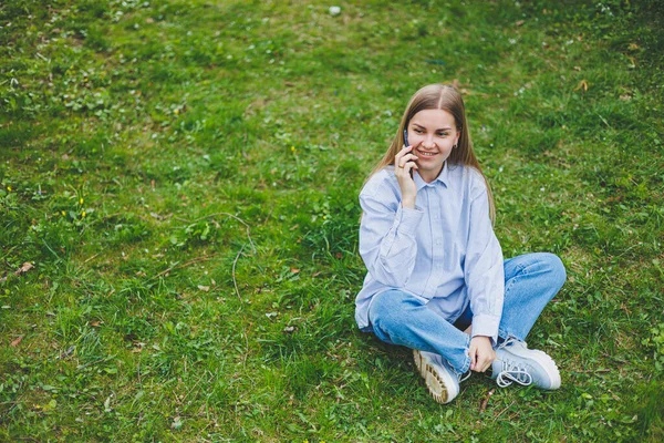 Şehir caddesinde akıllı telefon kullanarak yürüyen mutlu bir kadın. Güneş gözlüklü iş kadını dışarıda, ağacın altında cep telefonu kullanıyor. Kız mesaj yazıyor, sohbet ediyor, web sayfası kayıyor. Kameraya bakın.