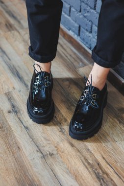 Beautiful woman with legs in fashionable clothes, stylish leather black patent leather lace-up shoes close-up. Women's image in spring style