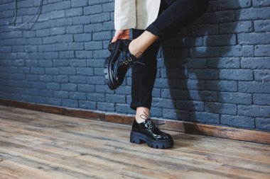 Şık giyinmiş güzel bacakları olan güzel bir kadın, şık, siyah deri, dantelli, yakın plan ayakkabıları olan. Bahar tarzında kadın imajı