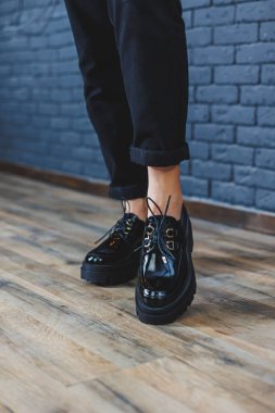 Beautiful woman with legs in fashionable clothes, stylish leather black patent leather lace-up shoes close-up. Womens image in spring style