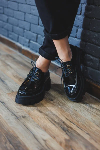 Şık giyinmiş güzel bacakları olan güzel bir kadın, şık, siyah deri, dantelli, yakın plan ayakkabıları olan. Bahar tarzında kadın imajı