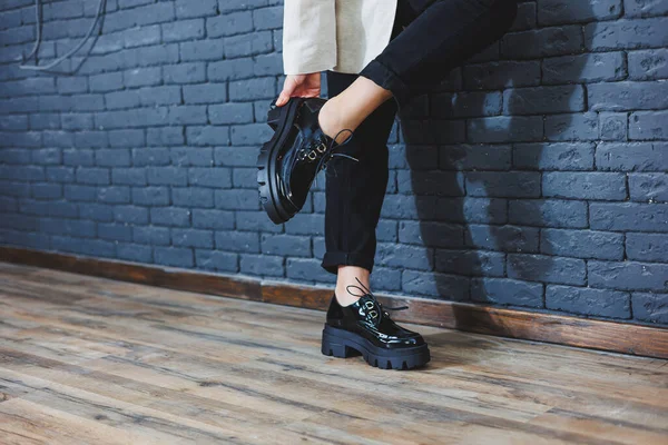 Şık giyinmiş güzel bacakları olan güzel bir kadın, şık, siyah deri, dantelli, yakın plan ayakkabıları olan. Bahar tarzında kadın imajı
