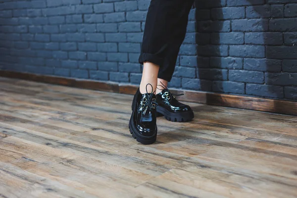 Şık giyinmiş güzel bacakları olan güzel bir kadın, şık, siyah deri, dantelli, yakın plan ayakkabıları olan. Bahar tarzında kadın imajı