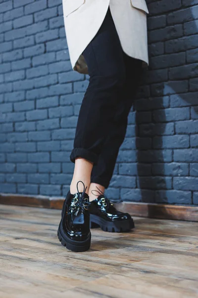 Beautiful woman with legs in fashionable clothes, stylish leather black patent leather lace-up shoes close-up. Womens image in spring style — Stock Photo, Image