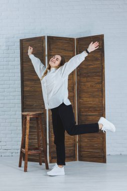 Güzel, şık bir kadın beyaz pamuklu gömlek ve siyah pantolon giyiyor. Beyaz spor ayakkabılı neşeli duygusal kız.