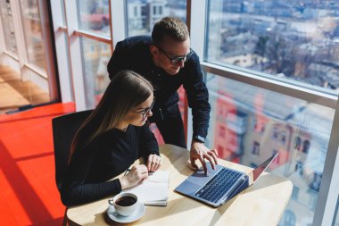 Başarılı iş ekibi, iş yerinde konuşan erkek ve kadın meslektaşlar, dizüstü bilgisayarla yeni bir projeyi tartışıyorlar, genç yöneticiler arkadaşça bir konuşma yapıyorlar, ofiste takım çalışmasında işbirliği yapıyorlar.