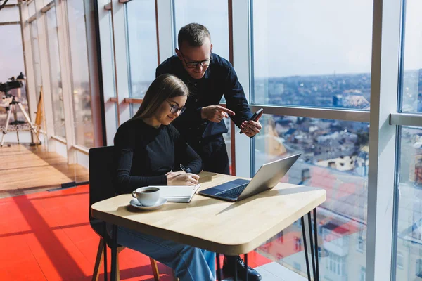 Dizüstü bilgisayar başında gözlüklü genç bir iş kadını modern bir ofiste iş arkadaşlarıyla iş toplantısı yapıyor. İş kariyeri konsepti. Boş alan, seçici odak