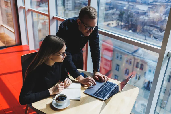 Gülümseyen genç erkek ve kadın yönetici masada oturuyor, bilgisayar ekranına bakıyor, girişimci yazılımları açıklıyor ya da iş arkadaşlarıyla online proje üzerinde çalışıyor..