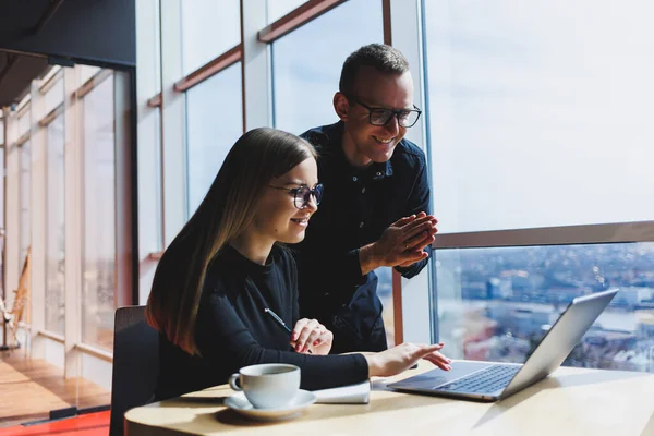 Gülümseyen genç erkek ve kadın yönetici masada oturuyor, bilgisayar ekranına bakıyor, girişimci yazılımları açıklıyor ya da iş arkadaşlarıyla online proje üzerinde çalışıyor..