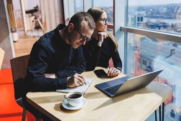 Gülümseyen genç erkek ve kadın yönetici masada oturuyor, bilgisayar ekranına bakıyor, girişimci yazılımları açıklıyor ya da iş arkadaşlarıyla online proje üzerinde çalışıyor..