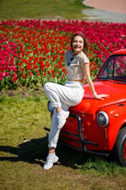 Renkli lale tarlalarında taşralı bir arabanın üzerine eğilmiş güzel bir kadının portresi. Chilliwack Tulip Ftstival. İngiliz Kolombiyası. Kanada