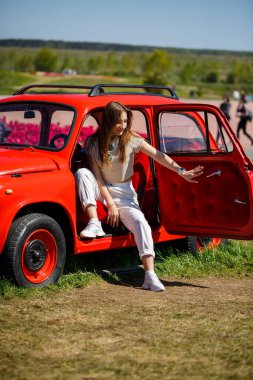 Renkli lale tarlalarında taşralı bir arabanın üzerine eğilmiş güzel bir kadının portresi. Chilliwack Tulip Ftstival. İngiliz Kolombiyası. Kanada