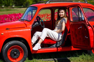 Renkli lale tarlalarında taşralı bir arabanın üzerine eğilmiş güzel bir kadının portresi. Chilliwack Tulip Ftstival. İngiliz Kolombiyası. Kanada