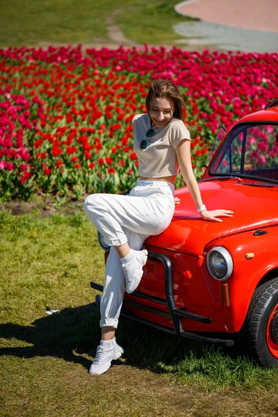 Renkli lale tarlalarında taşralı bir arabanın üzerine eğilmiş güzel bir kadının portresi. Chilliwack Tulip Ftstival. İngiliz Kolombiyası. Kanada