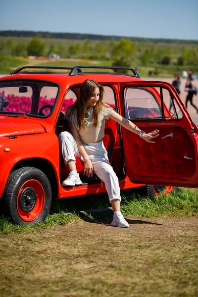 Renkli lale tarlalarında taşralı bir arabanın üzerine eğilmiş güzel bir kadının portresi. Chilliwack Tulip Ftstival. İngiliz Kolombiyası. Kanada