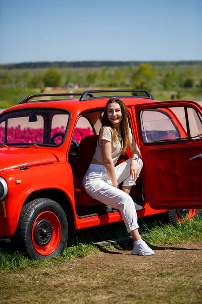 Renkli lale tarlalarında taşralı bir arabanın üzerine eğilmiş güzel bir kadının portresi. Chilliwack Tulip Ftstival. İngiliz Kolombiyası. Kanada