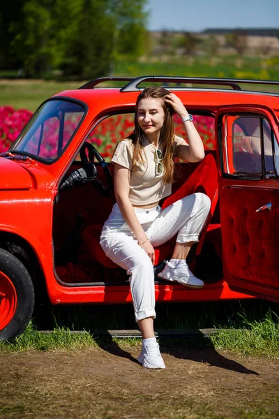 Renkli lale tarlalarında taşralı bir arabanın üzerine eğilmiş güzel bir kadının portresi. Chilliwack Tulip Ftstival. İngiliz Kolombiyası. Kanada