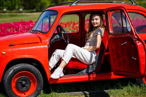 Renkli lale tarlalarında taşralı bir arabanın üzerine eğilmiş güzel bir kadının portresi. Chilliwack Tulip Ftstival. İngiliz Kolombiyası. Kanada