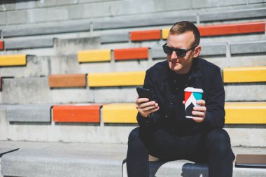 Elinde cep telefonu olan takım elbiseli gülümseyen iş adamının fotoğrafı.