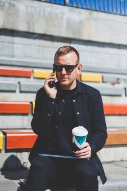 Elinde cep telefonu olan takım elbiseli gülümseyen iş adamının fotoğrafı.