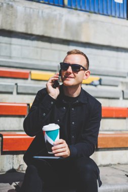 Elinde cep telefonu olan takım elbiseli gülümseyen iş adamının fotoğrafı.