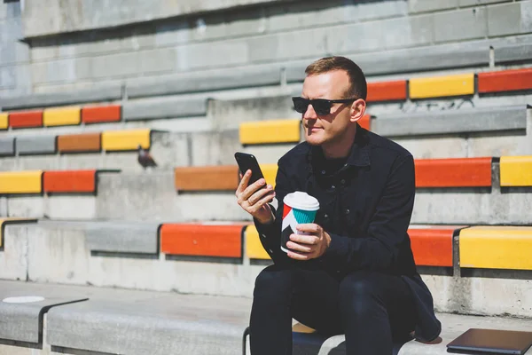 Elinde cep telefonu olan takım elbiseli gülümseyen iş adamının fotoğrafı.