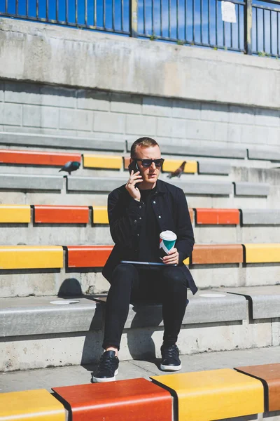 Elinde cep telefonu olan takım elbiseli gülümseyen iş adamının fotoğrafı.