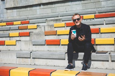 Elinde cep telefonu olan takım elbiseli gülümseyen iş adamının fotoğrafı.