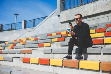 Elinde cep telefonu olan takım elbiseli gülümseyen iş adamının fotoğrafı.