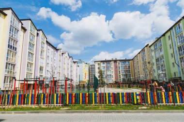 Yüksek katlı yeni binalar. Yeni bir alanda balkonlu daireler. Modern konut binaları. Bir iskan binasının avlusunda çocuk parkı.