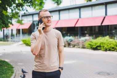 Kurye çantası taşıyan, şık gözlükler takıp kameraya bakan olgun bir iş adamının portresi. Gülümseyen orta yaşlı bir adam akıllı telefon kullanıyor, sokakta dikiliyor. Mobil bankacılık kavramı
