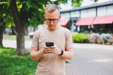 Kurye çantası taşıyan, şık gözlükler takıp kameraya bakan olgun bir iş adamının portresi. Gülümseyen orta yaşlı bir adam akıllı telefon kullanıyor, sokakta dikiliyor. Mobil bankacılık kavramı