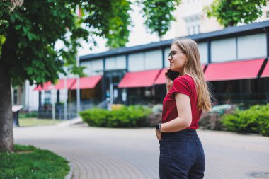 Gri kazaklı, mavi kotlu ve gözlüklü genç bir bayan kaldırımda duruyor. New York 'ta alışveriş torbaları taşıyor ve akıllı telefondan mesajlaşıyor.