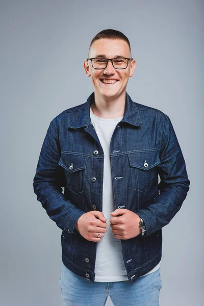 Live a rich life. Positive emotions. Portrait of a young attractive man in a white t-shirt and denim jacket. Men's clothing from the denim collection