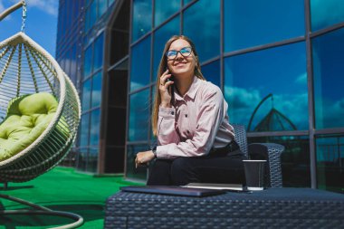 Genç mutlu bir kadın cep telefonuyla gülümsüyor ve konuşuyor, iş kadını bir kafede netbook ile masada dinlenirken not alıyor.