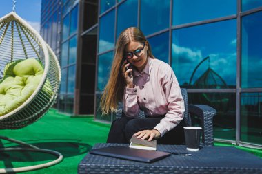 Genç mutlu bir kadın cep telefonuyla gülümsüyor ve konuşuyor, iş kadını bir kafede netbook ile masada dinlenirken not alıyor.