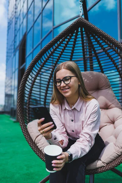 Güneşli bir günde açık havada kahve molası veren gözlüklü neşeli bir iş kadınının portresi. Ofisin arka planında otururken telefonda konuşan başarılı bir kadın yönetici.