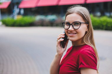 Gri kazaklı, mavi kotlu ve gözlüklü genç bir bayan kaldırımda duruyor. New York 'ta alışveriş torbaları taşıyor ve akıllı telefondan mesajlaşıyor.