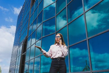 Çekici kadın blogcu elinde modern bir alet tutuyor, düşünceli ve hayalperest görünüyor, cep telefonu tutan genç blogcu, sosyal medyada paylaşım yapma fikrini düşünüyor.