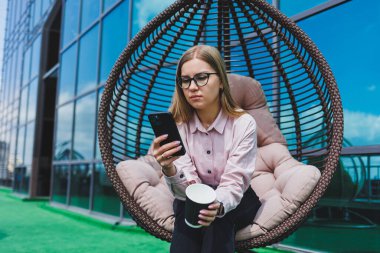 Güneşli bir günde açık havada kahve molası veren gözlüklü neşeli bir iş kadınının portresi. Ofisin arka planında otururken telefonda konuşan başarılı bir kadın yönetici.