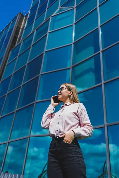 Attractive female blogger holding a modern gadget in her hands, looking thoughtful and daydreaming, young blogger holding a mobile phone, thinking about an idea for posting on social media
