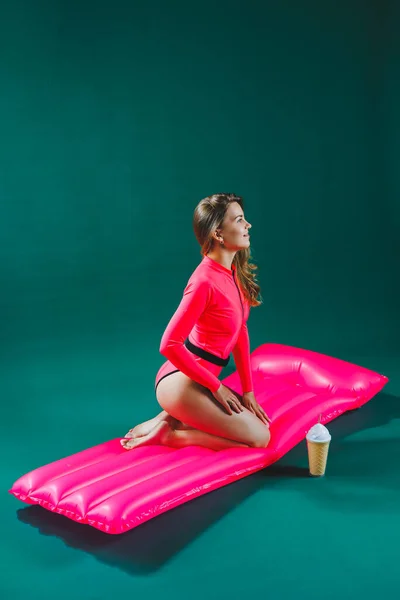 분홍색 수영복을 아름다운 여자가 부풀어 오르는 분홍색 매트리스 있습니다 여름의 — 스톡 사진