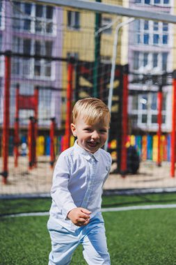 Çocuk parkta koşar. Beyaz gömlekli ve pantolonlu bir çocuk. Yeşil çimen ya da tarla. Çimleri biçtim. Ormanda yürü ve oyna. Etkin sporlar.