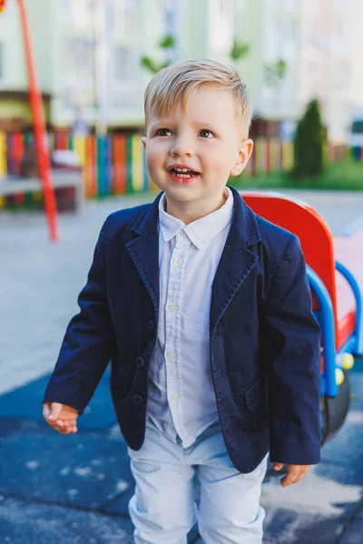 A little boy 2 years old in a shirt and jacket stands on the street. Children\'s classic costume for the holiday. Children\'s fashion.